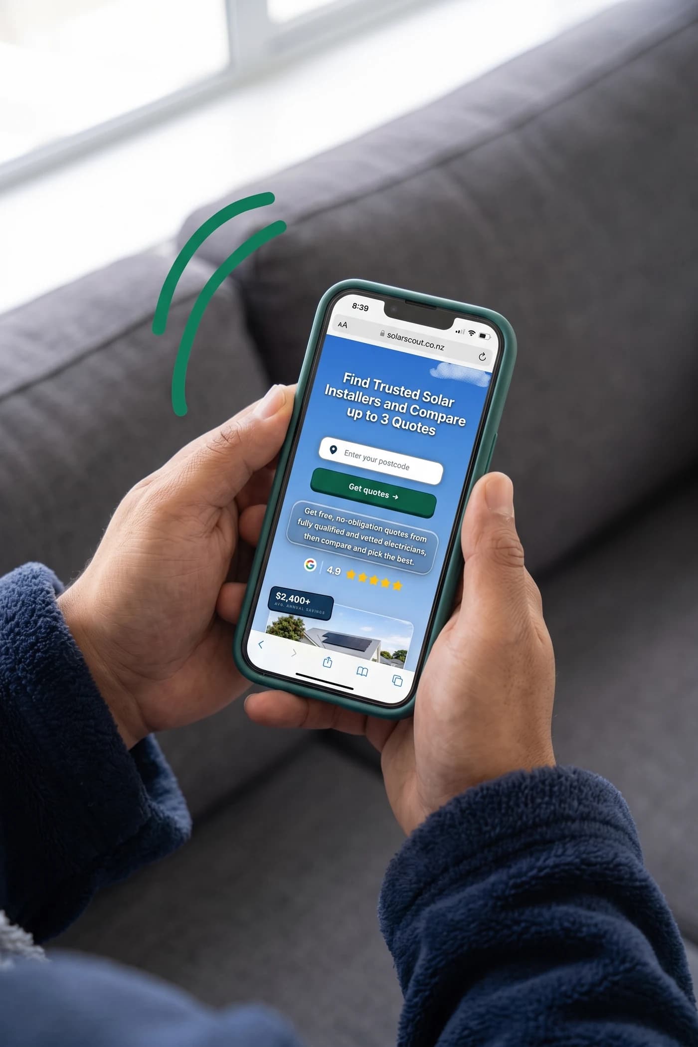 A homeowner on a sofa, holding a phone showing the Solar Scout home page.